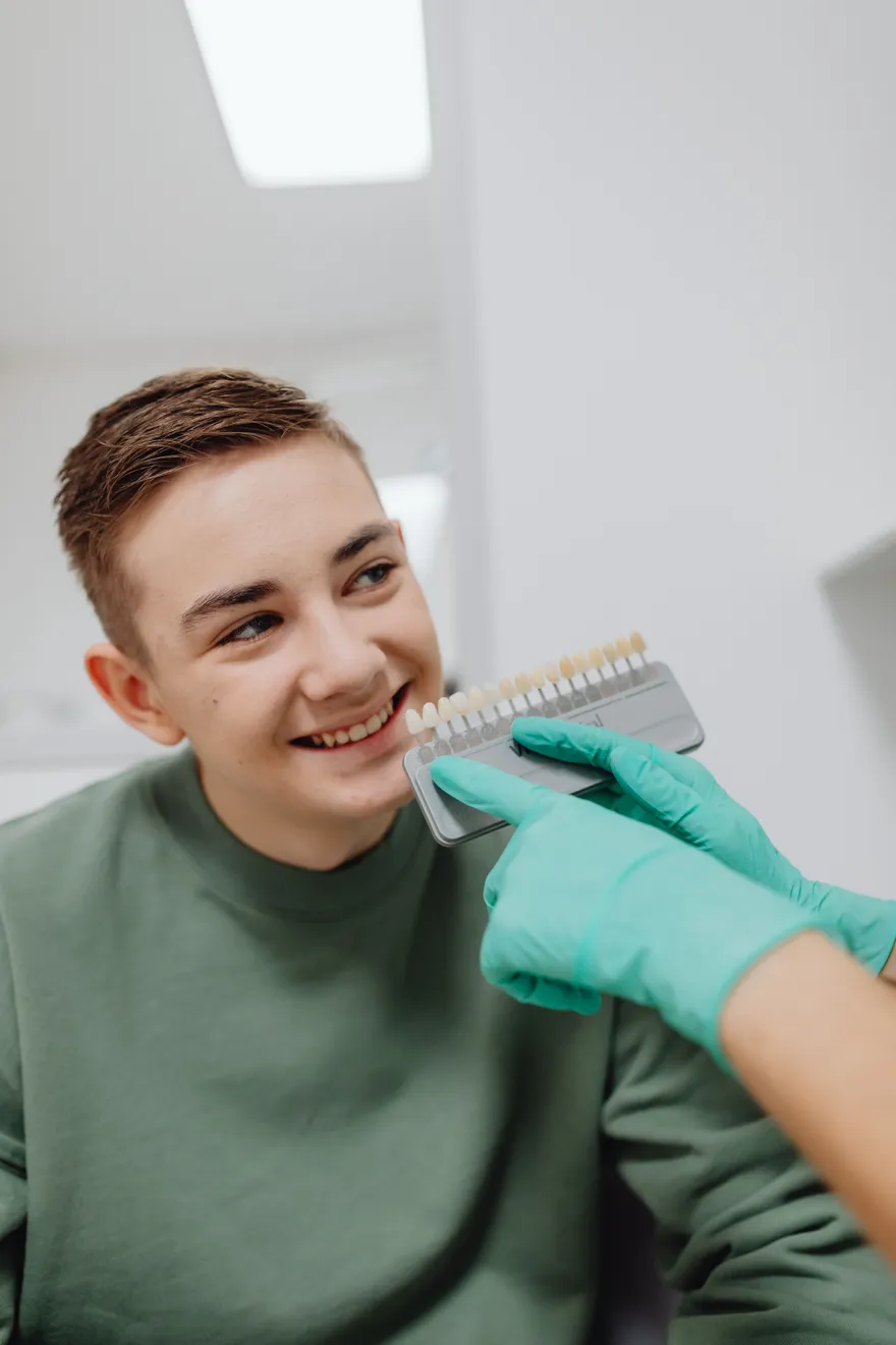 A patient smiling while the dentist matches her tooth shade